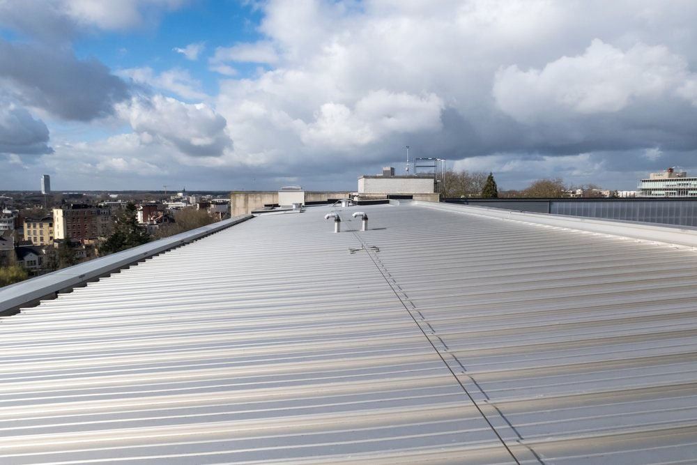 A Metal Roof Stretches Toward a City Skyline Under a Cloudy Sky — MJD Roofing Sunshine Coast in Cooroy, QLD
