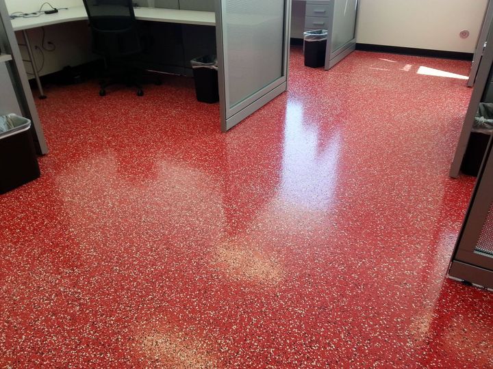 Red speckled floor in an office area with cubicles and a chair visible.