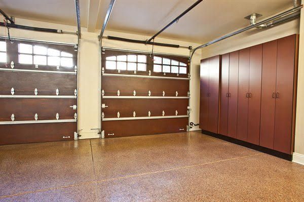Empty garage interior with brown walls, built-in shelves, and a large wooden cabinet on the right