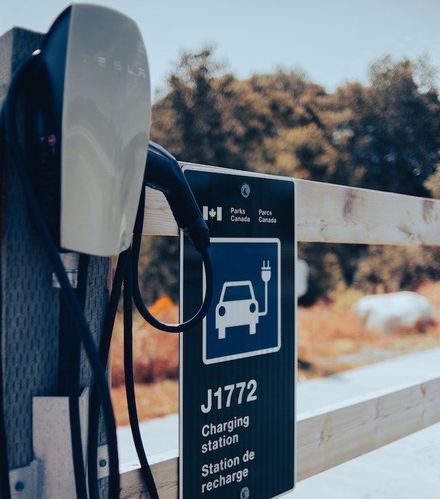 Borne de recharge pour véhicule électrique avec panneau J1772; extérieur, panneau bleu et blanc, câble de recharge et drapeau canadien.