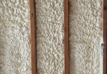 A close up of a wall with foam insulation and wooden beams.