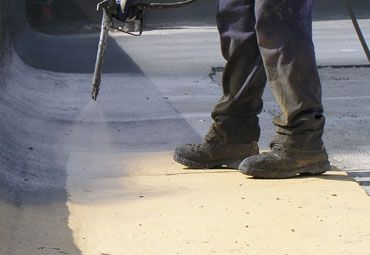 A man is spraying a coating on a concrete surface.