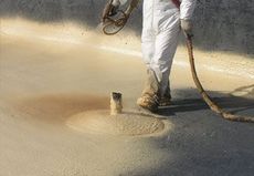 A man is spraying foam on a concrete surface.