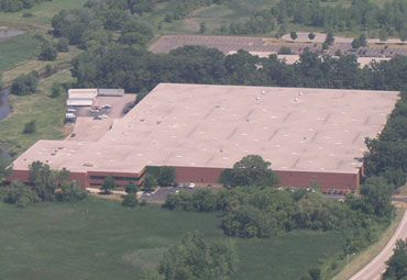 An aerial view of a large warehouse surrounded by trees and grass.
