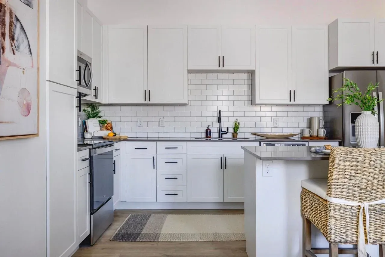 Modern white kitchen with stainless steel appliances and subway tile backsplash at Aria in Syracuse, UT.