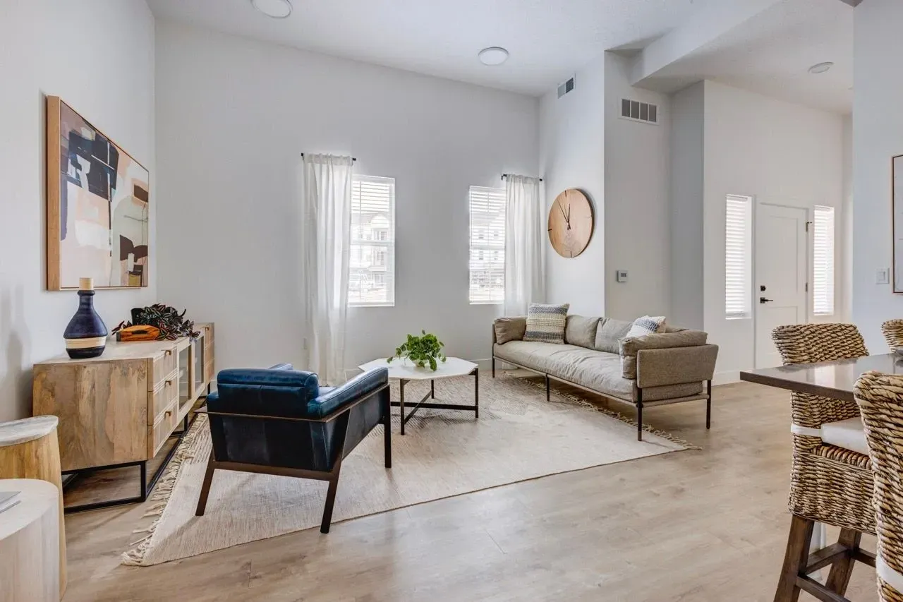 Modern living room with a blue armchair, a beige sofa, and a coffee table at Aria in Syracuse, UT.