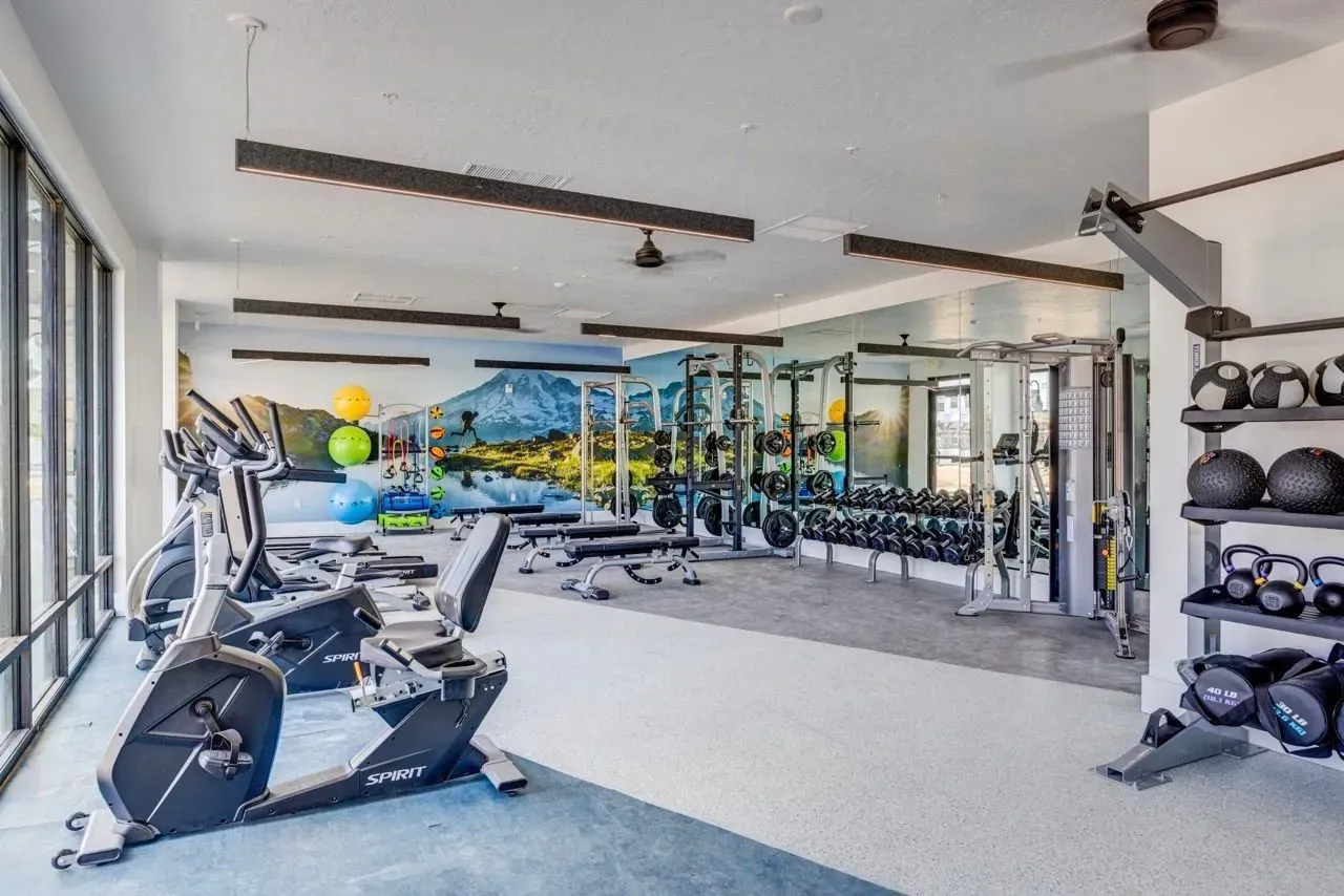 Well-equipped fitness center with cardio machines, free weights, and a scenic mural at Aria in Syracuse, UT.