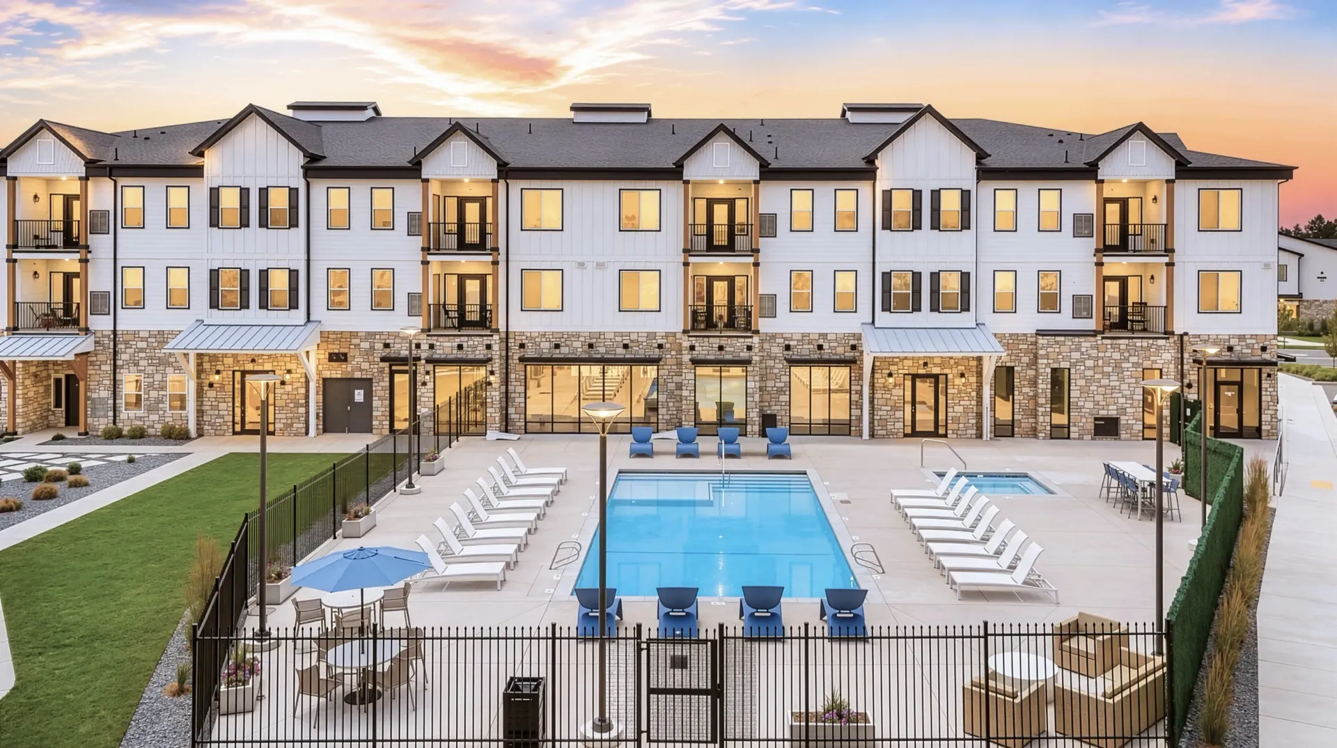 Modern apartment building with a resort-style pool and lounge chairs at Aria in Syracuse, UT.
