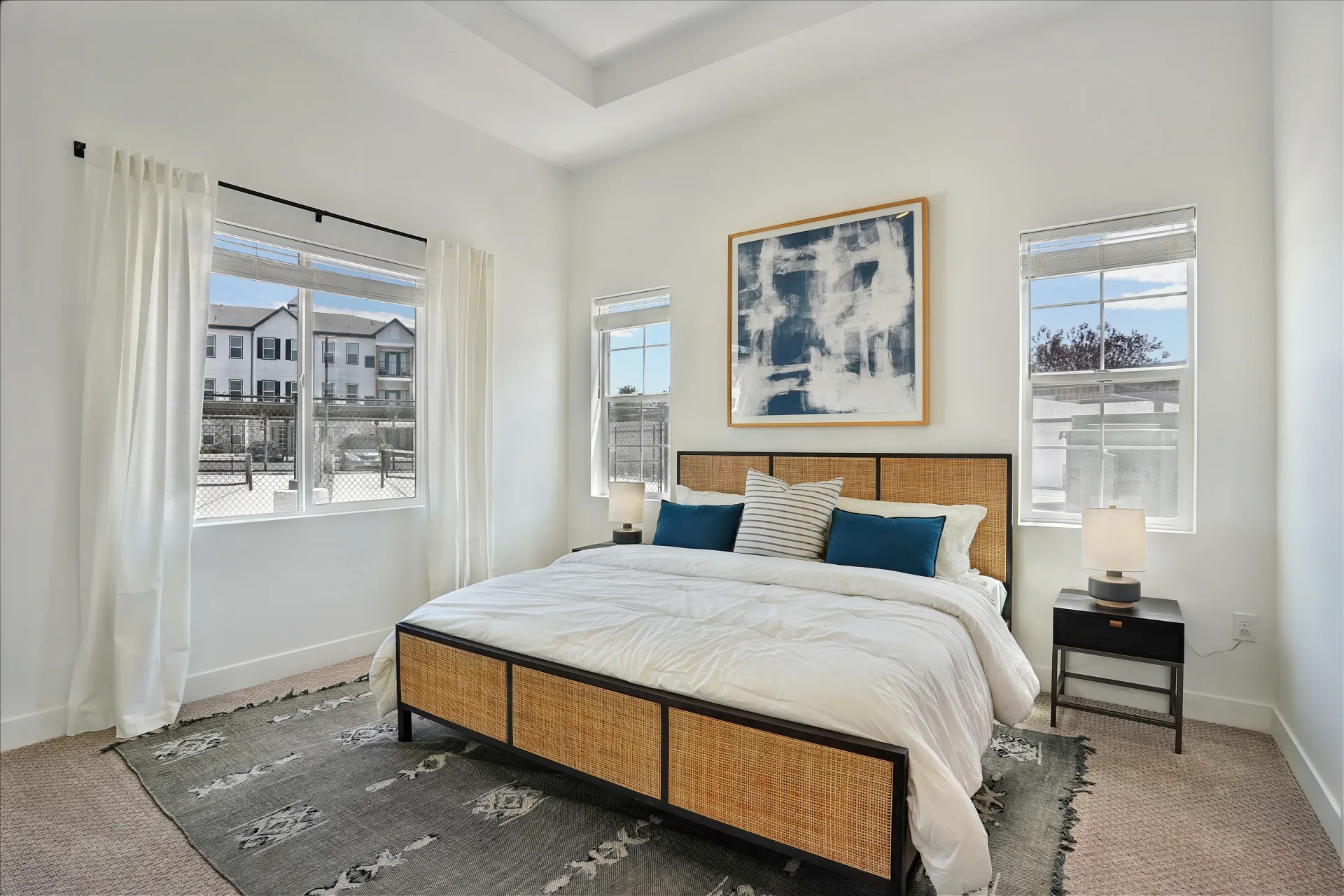 Modern bedroom with a king-size bed, large windows, and abstract art at Aria in Syracuse, UT.