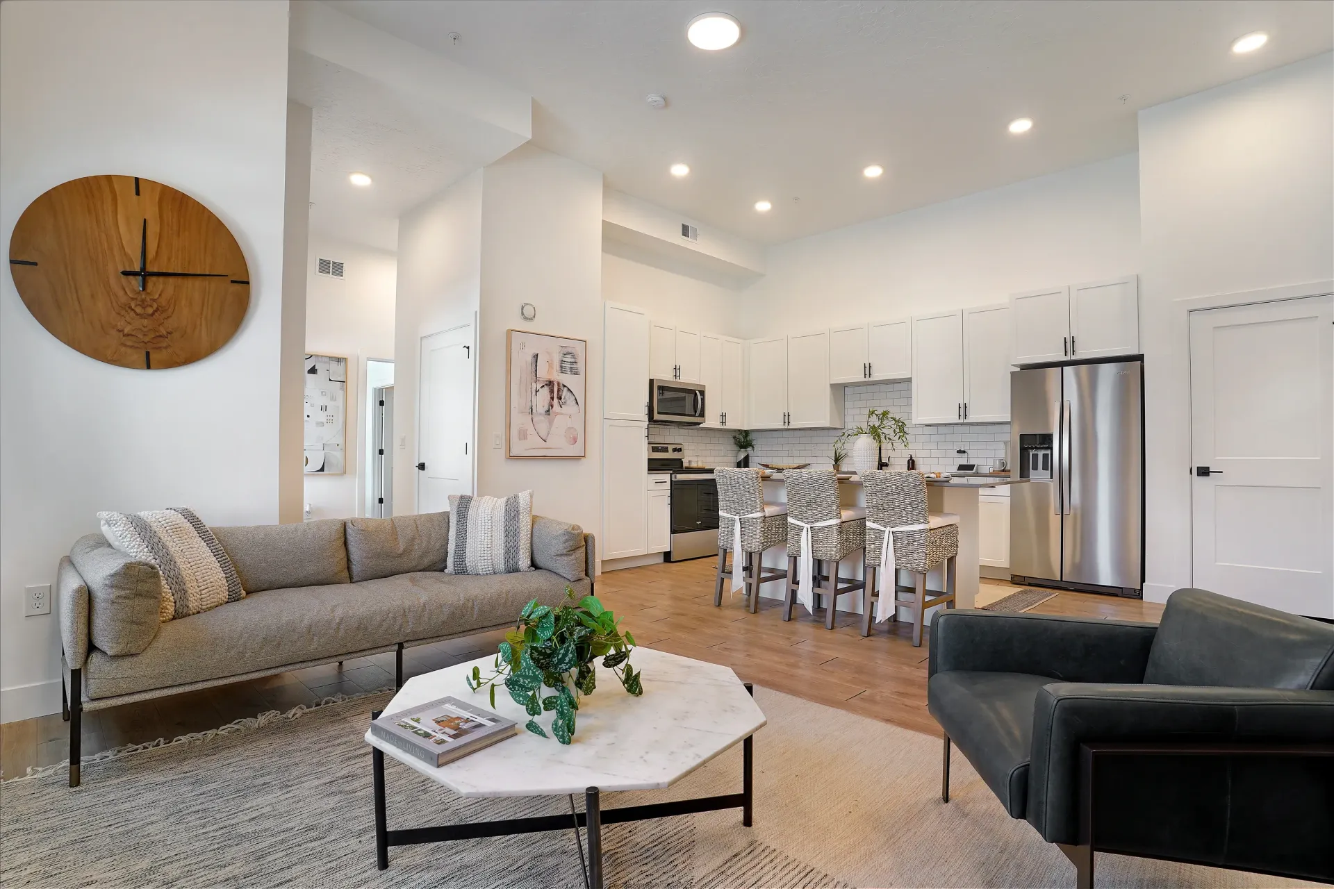 Modern living room and kitchen with sleek white cabinets and stainless steel appliances at Aria in Syracuse, UT.