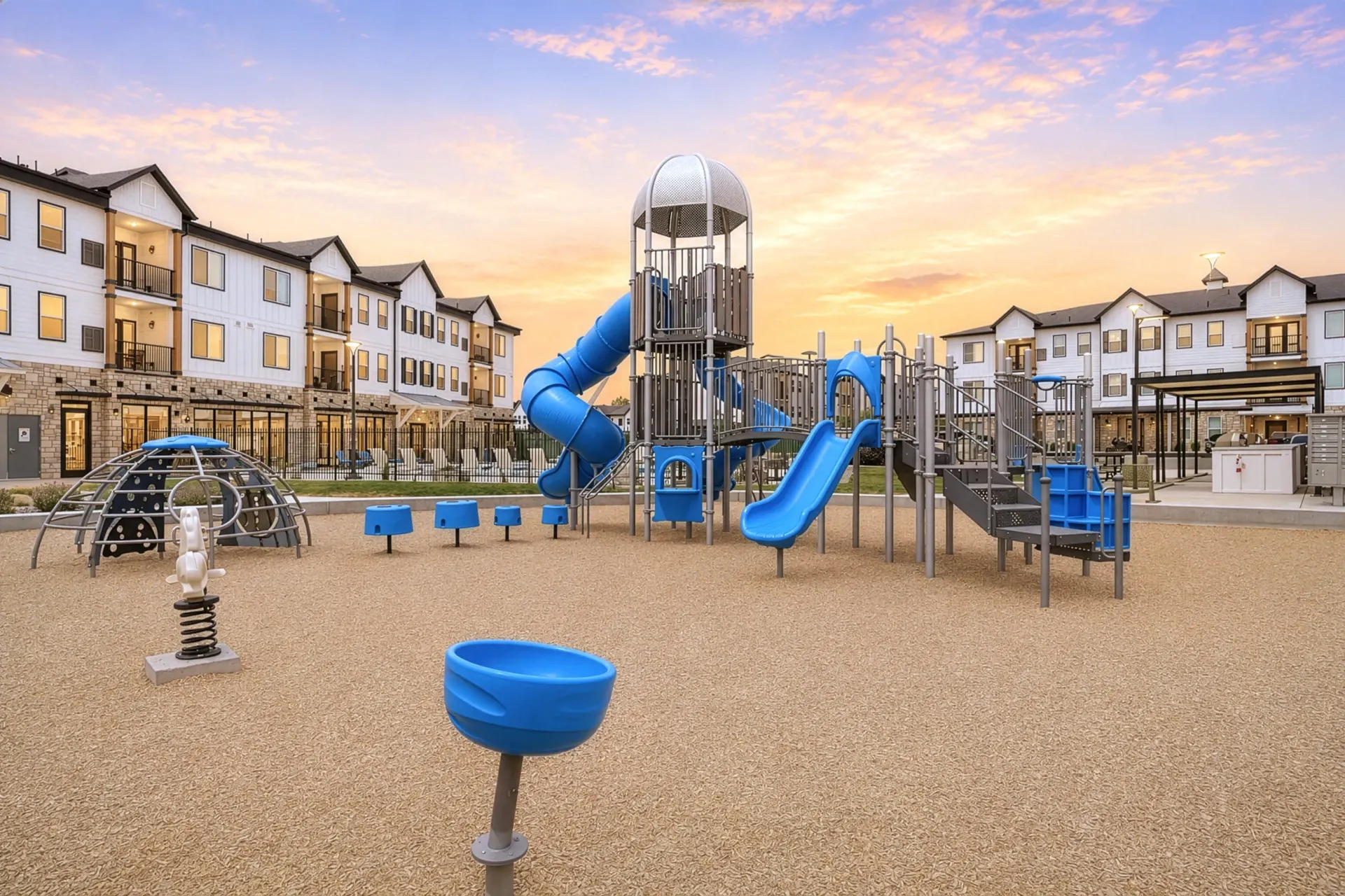 Playground with slides and climbing structures in front of apartment buildings at Aria in Syracuse, UT.