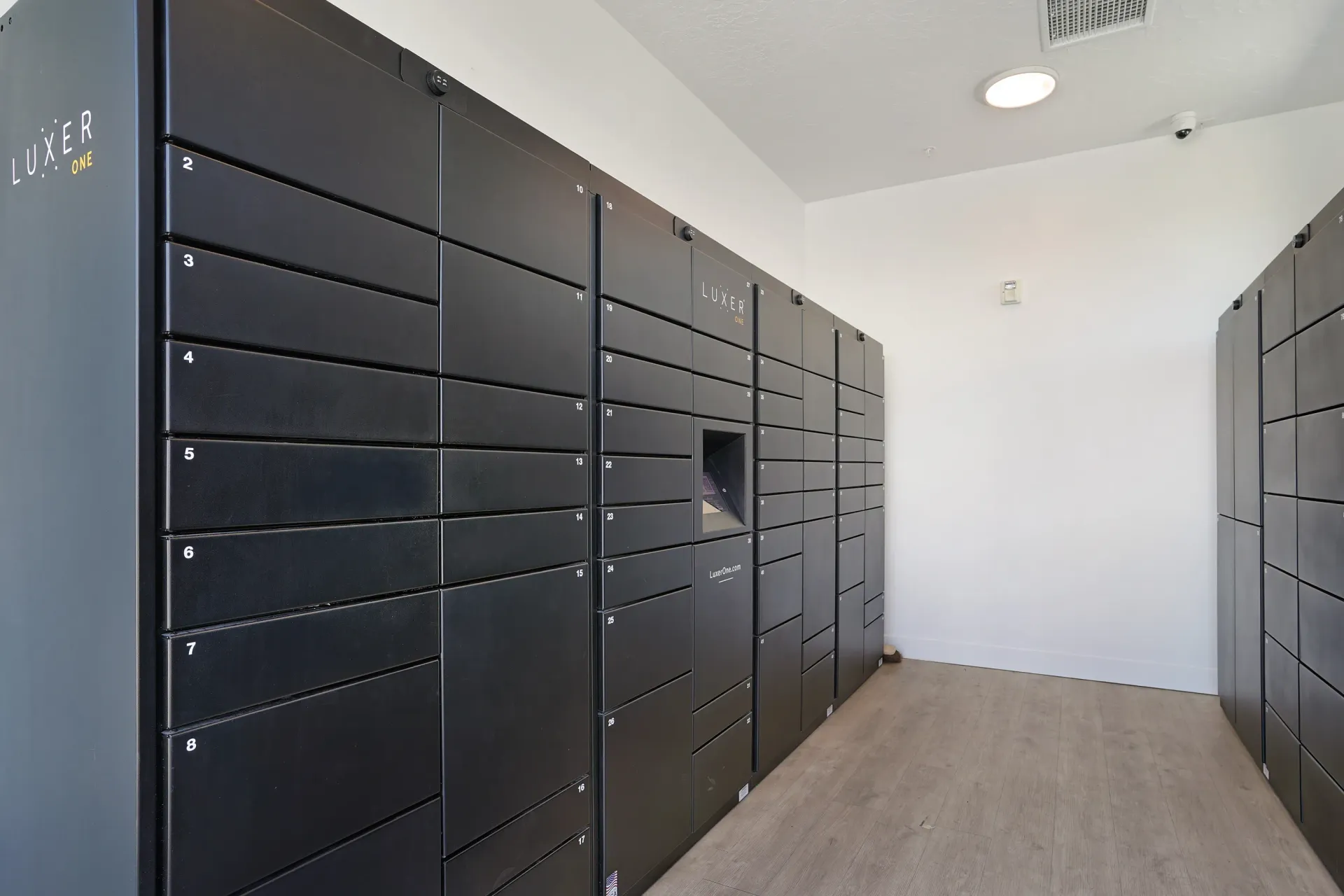 Luxer One package lockers with numbered compartments and a touchscreen interface at Aria in Syracuse, UT.