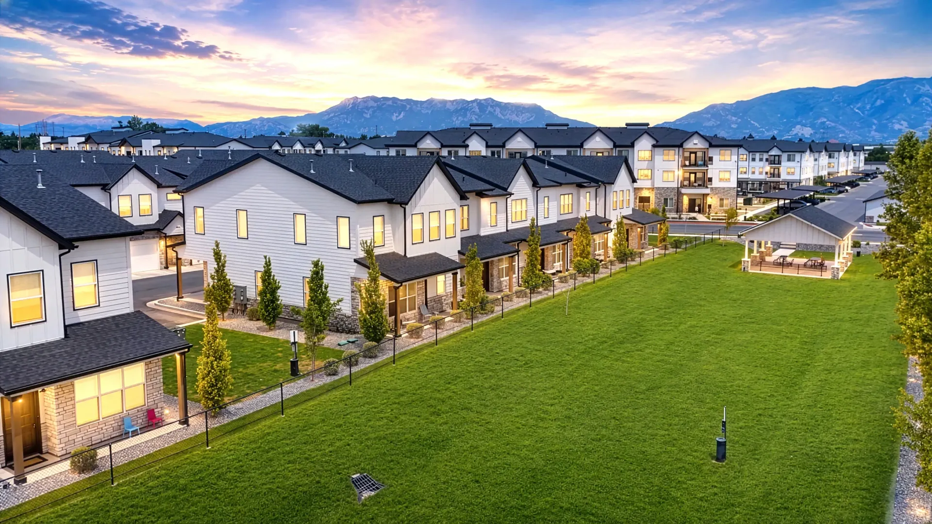 Exterior view of townhouses and apartment buildings with mountains in the background at Aria in Syracuse, UT.