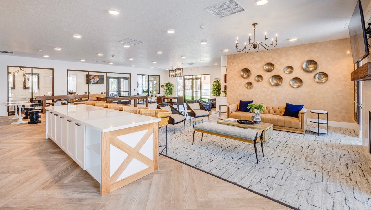 Aria community lounge with beige couches, chairs, a long white island, and wall decor.