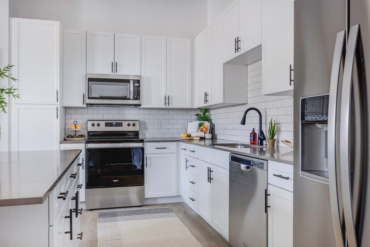 Aria white kitchen with stainless steel appliances and a black faucet.