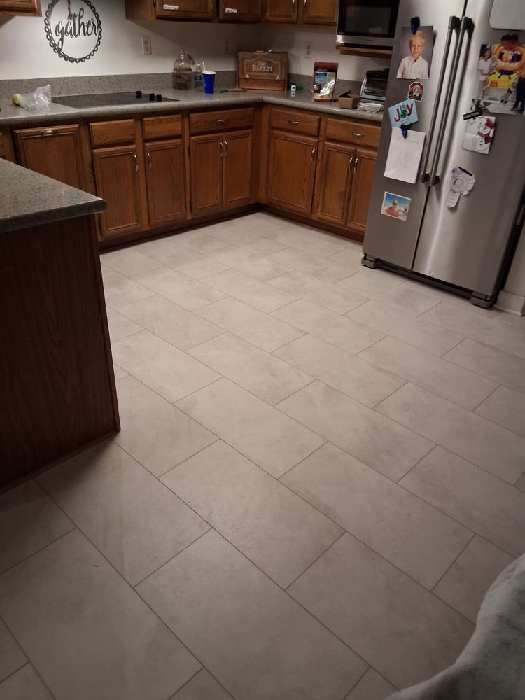 Kitchen with wood cabinets, tile floor, stainless fridge, and countertop clutter.
