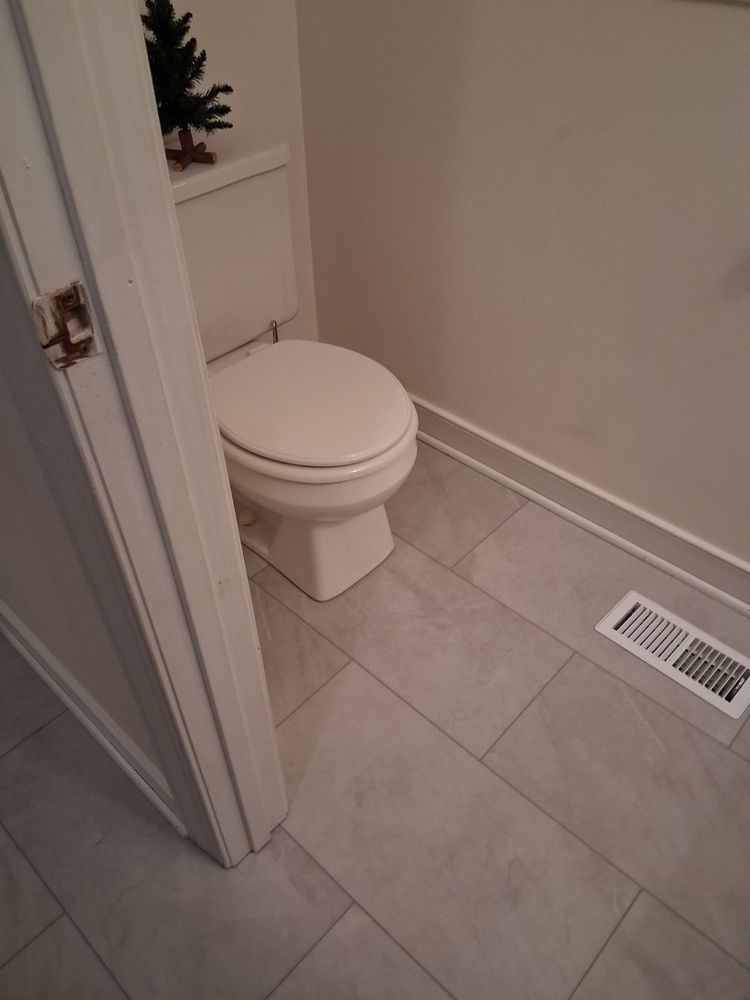 Small bathroom with a toilet, light tile floor, and a wall vent near the baseboard.