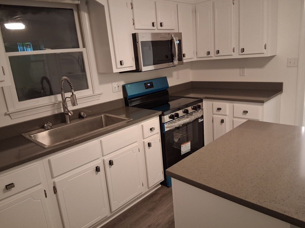 Modern kitchen with white cabinets, stainless sink and appliances, and gray countertops