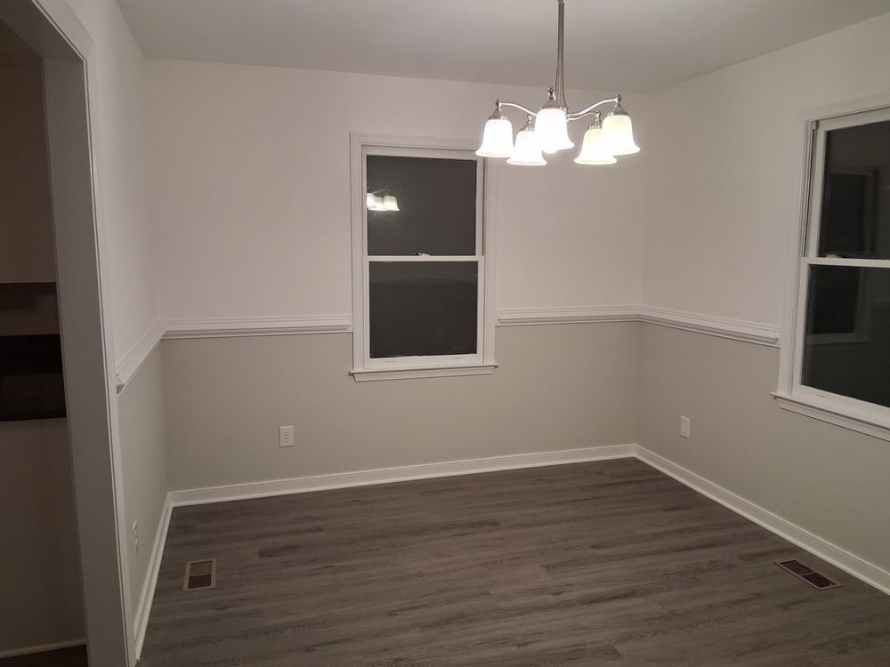 Empty dining room with gray walls, wood flooring, and a hanging ceiling light fixture