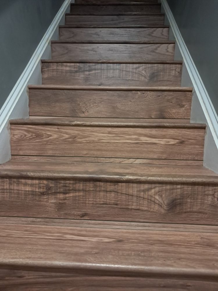Wooden staircase with brown steps and white side trim, viewed from the bottom.