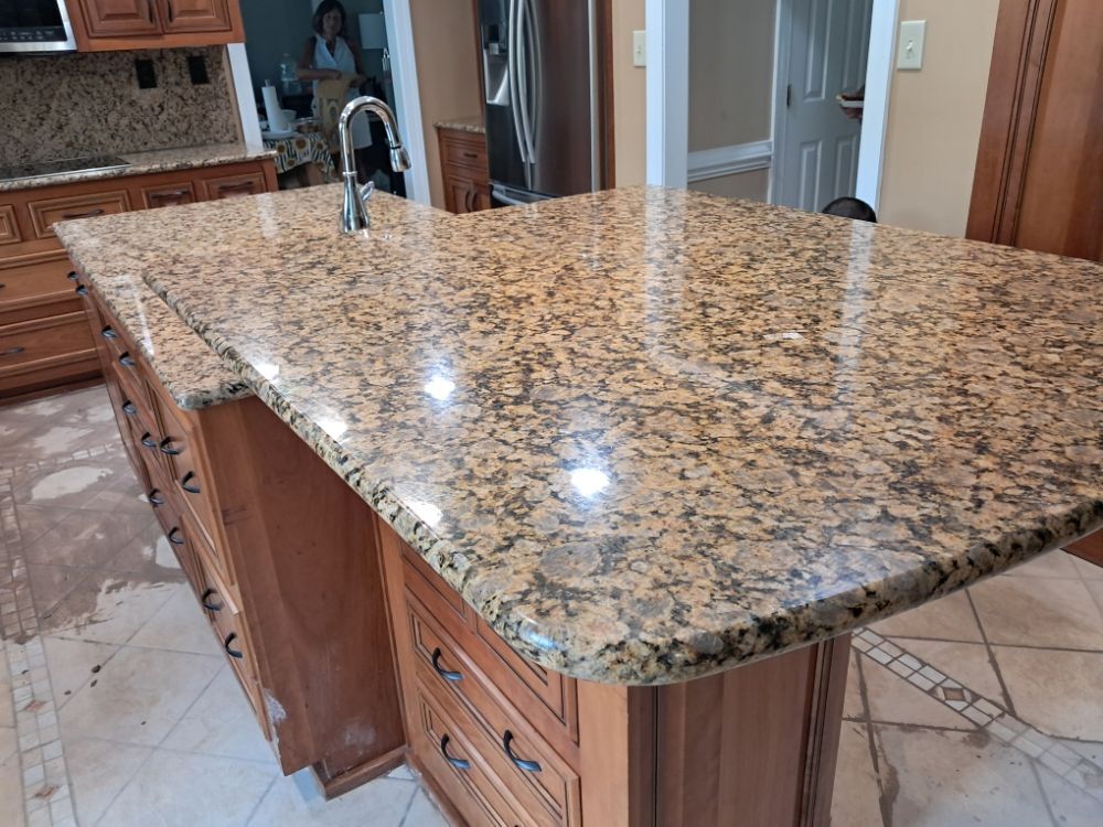 Granite kitchen island with speckled countertop and wooden cabinets under bright lights