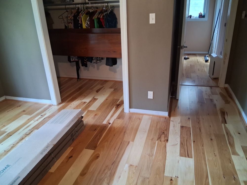 Room with hardwood floors, open closet, and hallway leading to a doorway