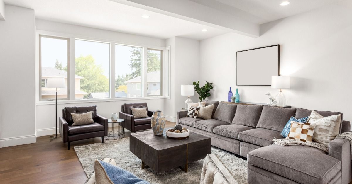 Bright modern living room featuring a gray sectional sofa, two armchairs, a coffee table, and large