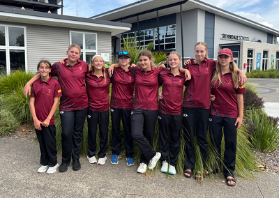 Group of teammates in matching maroon shirts posing outside a building