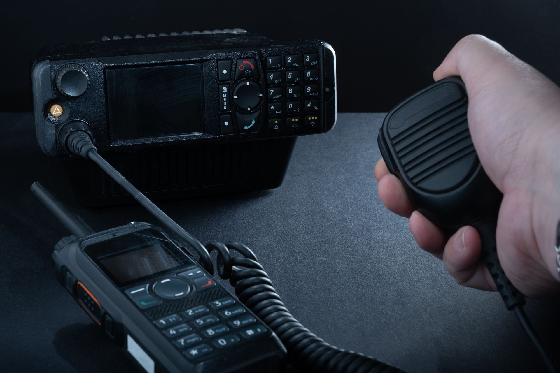 A person is holding a microphone in front of a walkie talkie.