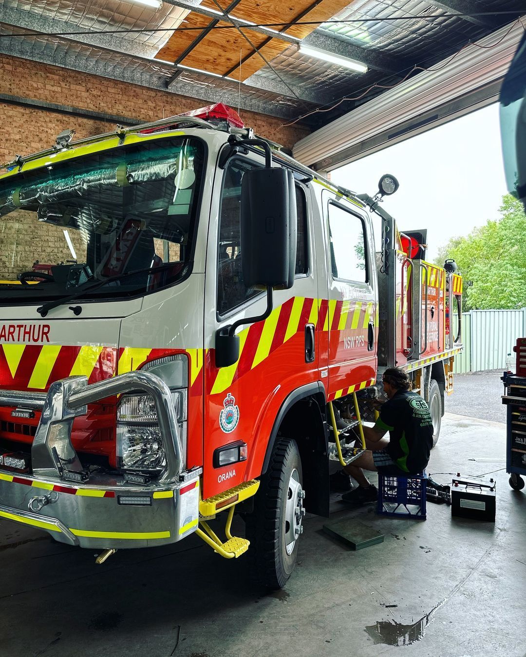 A man is working on a fire truck in a garage.