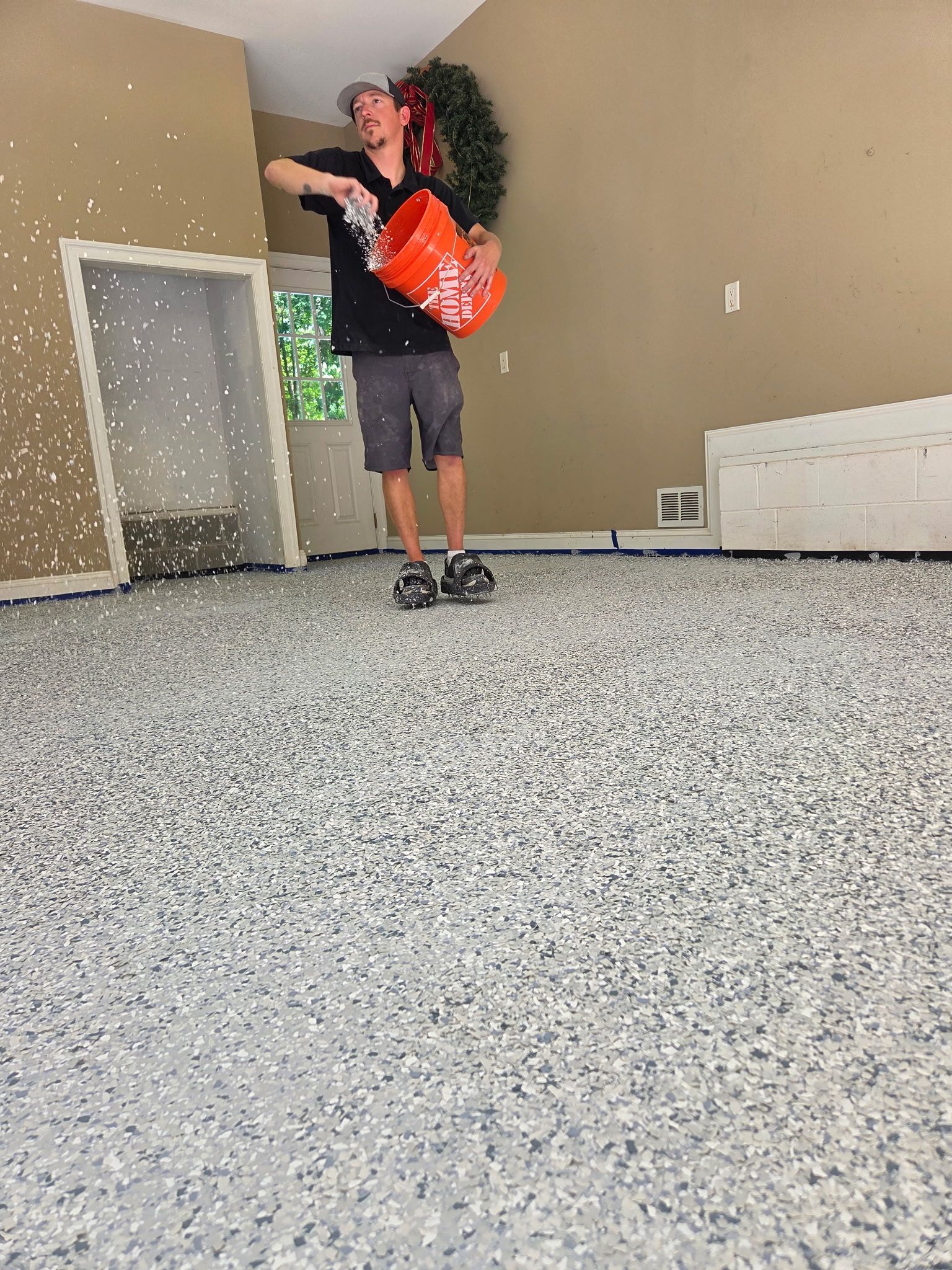 Person standing in an empty room with a bright orange backpack, next to a small door opening.