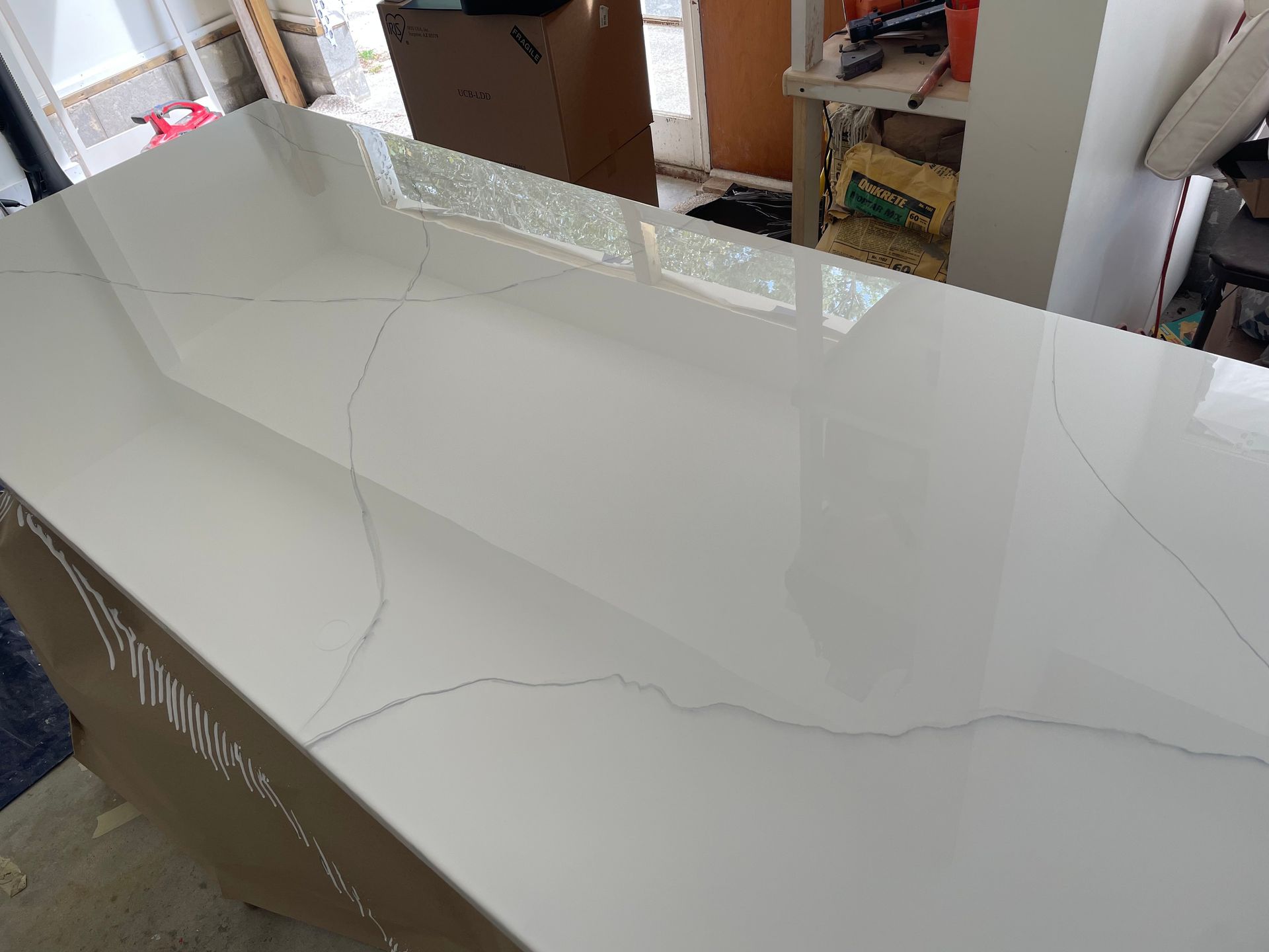 White glossy tabletop with visible hairline cracks in a workshop or showroom setting