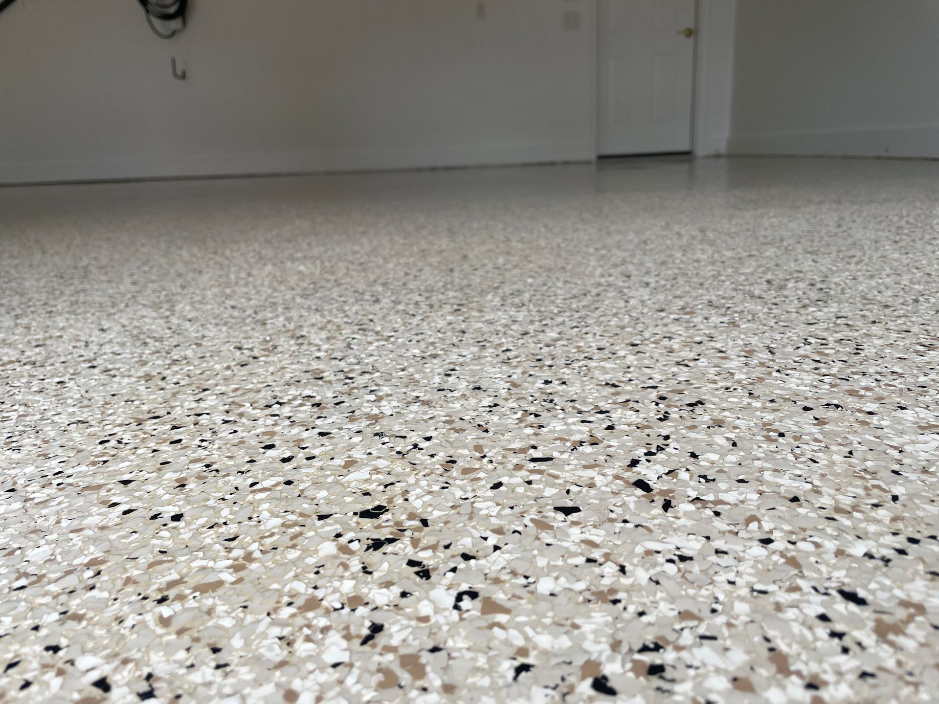 Empty speckled terrazzo floor in a bare room with white walls and a door