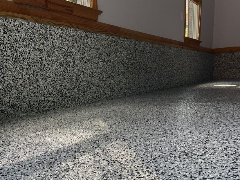 Empty speckled stone floor with wood-paneled wall and sunlight patches from windows
