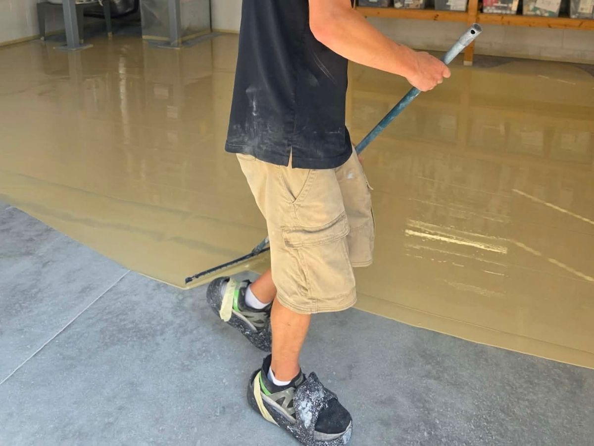 Person walking indoors, holding a handle, wearing khaki shorts and black sneakers on a wet floor.
