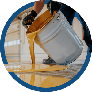Worker tipping white paint bucket, spilling orange paint onto a floor