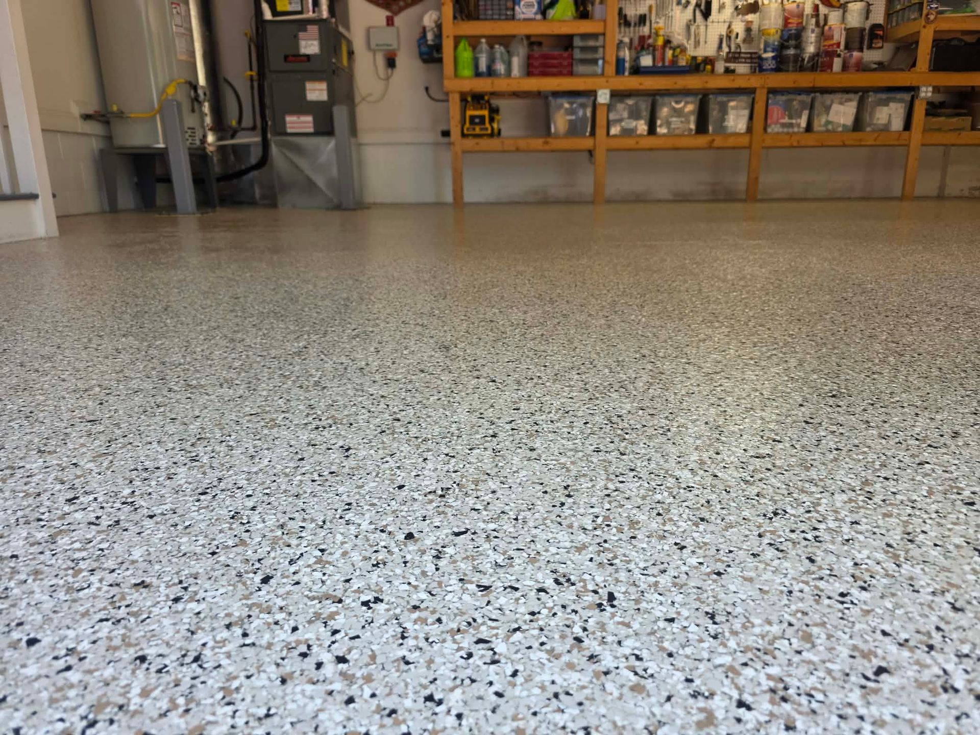 Empty speckled garage floor with shelves and tools in the background