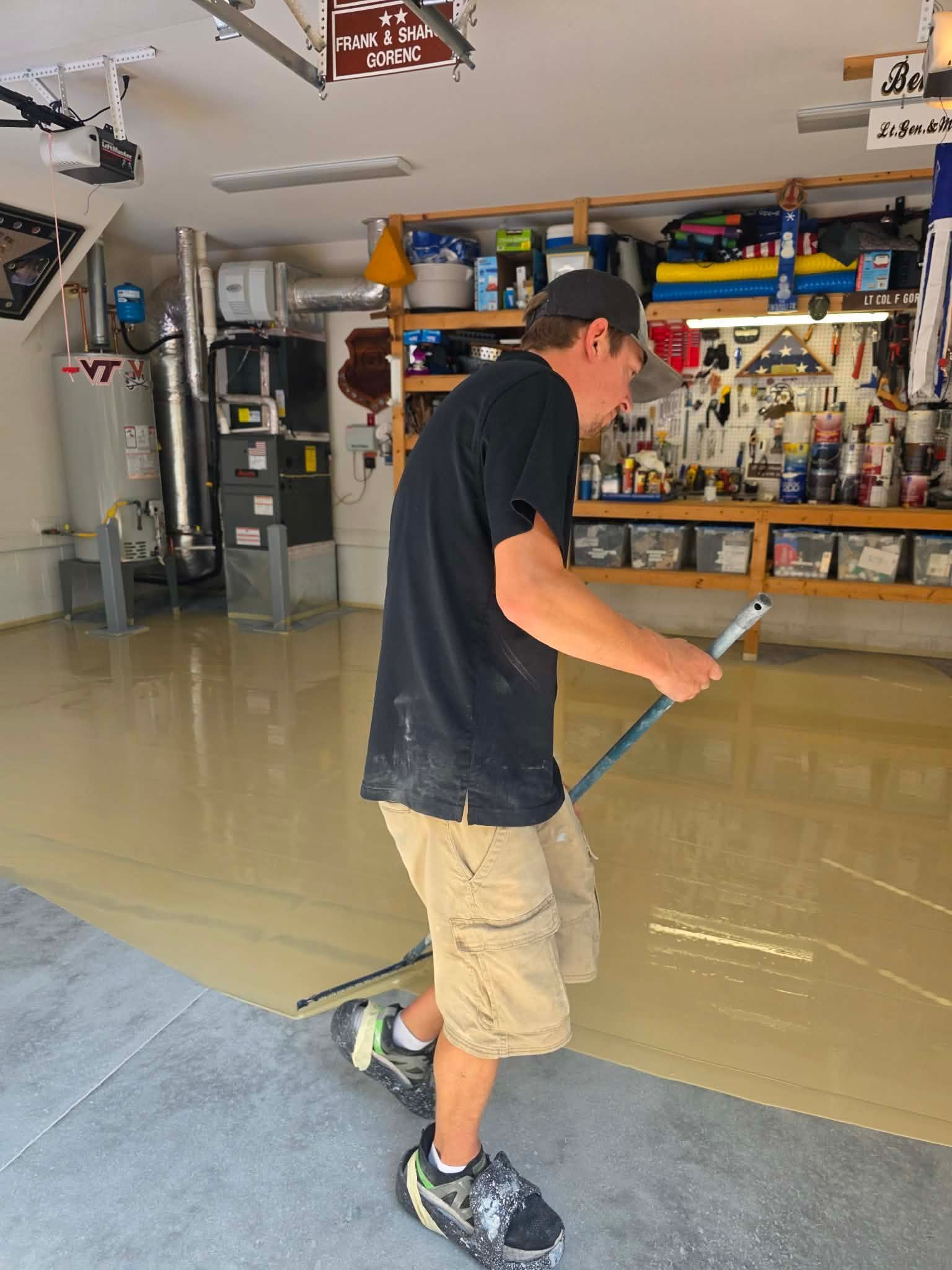 Person skateboarding in a garage, wearing a black shirt and tan shorts.