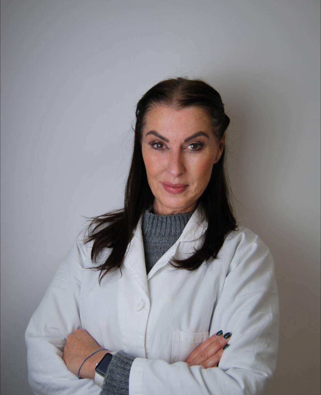 Una donna in camice bianco con le braccia incrociate