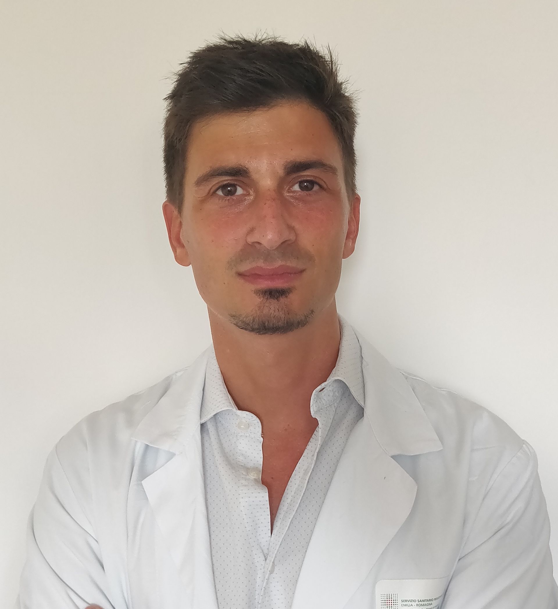 Un uomo in camice bianco è in piedi con le braccia incrociate