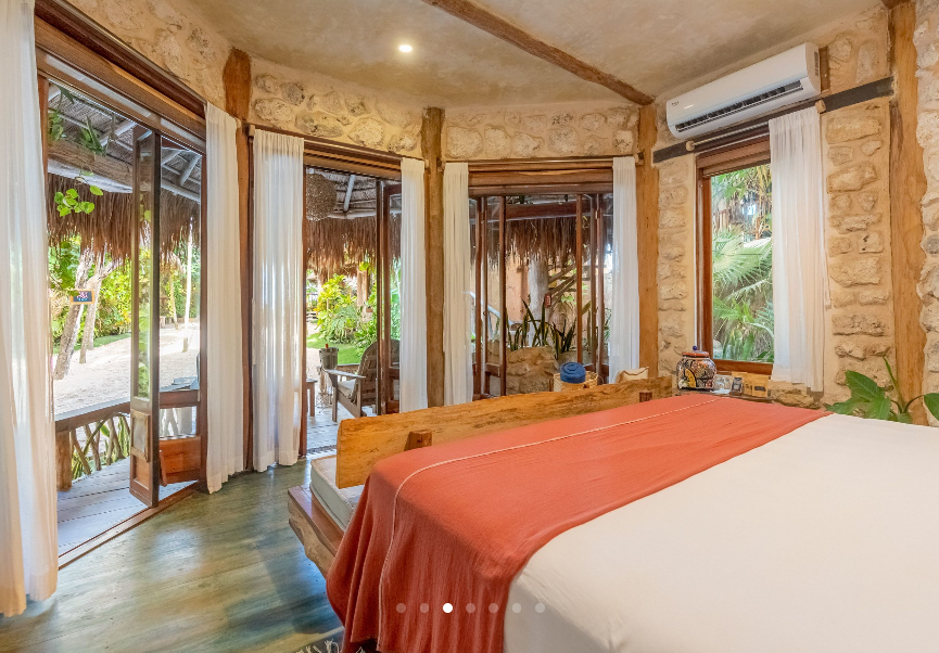 Bedroom with bed, open doors to exterior, stone and wood construction.