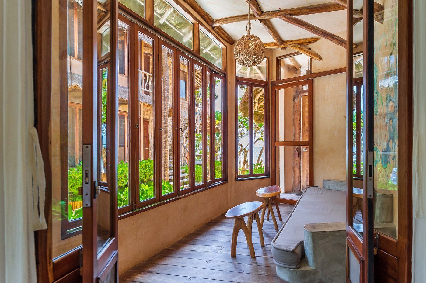 Sunroom with wooden-framed windows, a stone bench, and a hanging light fixture.