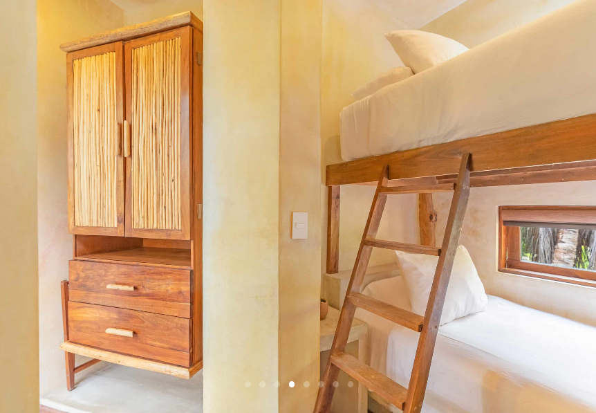Wooden bunk beds and closet in a room with light yellow walls.