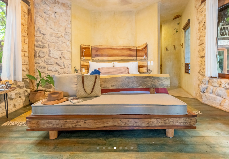 Bedroom with rustic wooden bed and headboard, stone walls, and natural light.
