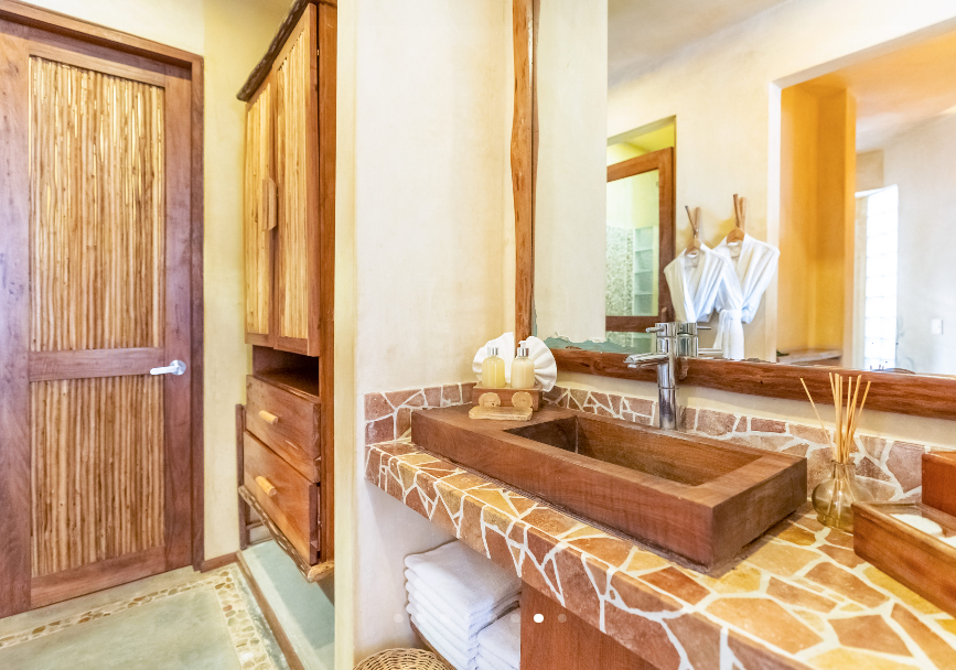 Bathroom with wood vanity, mosaic countertop, and wooden closet.