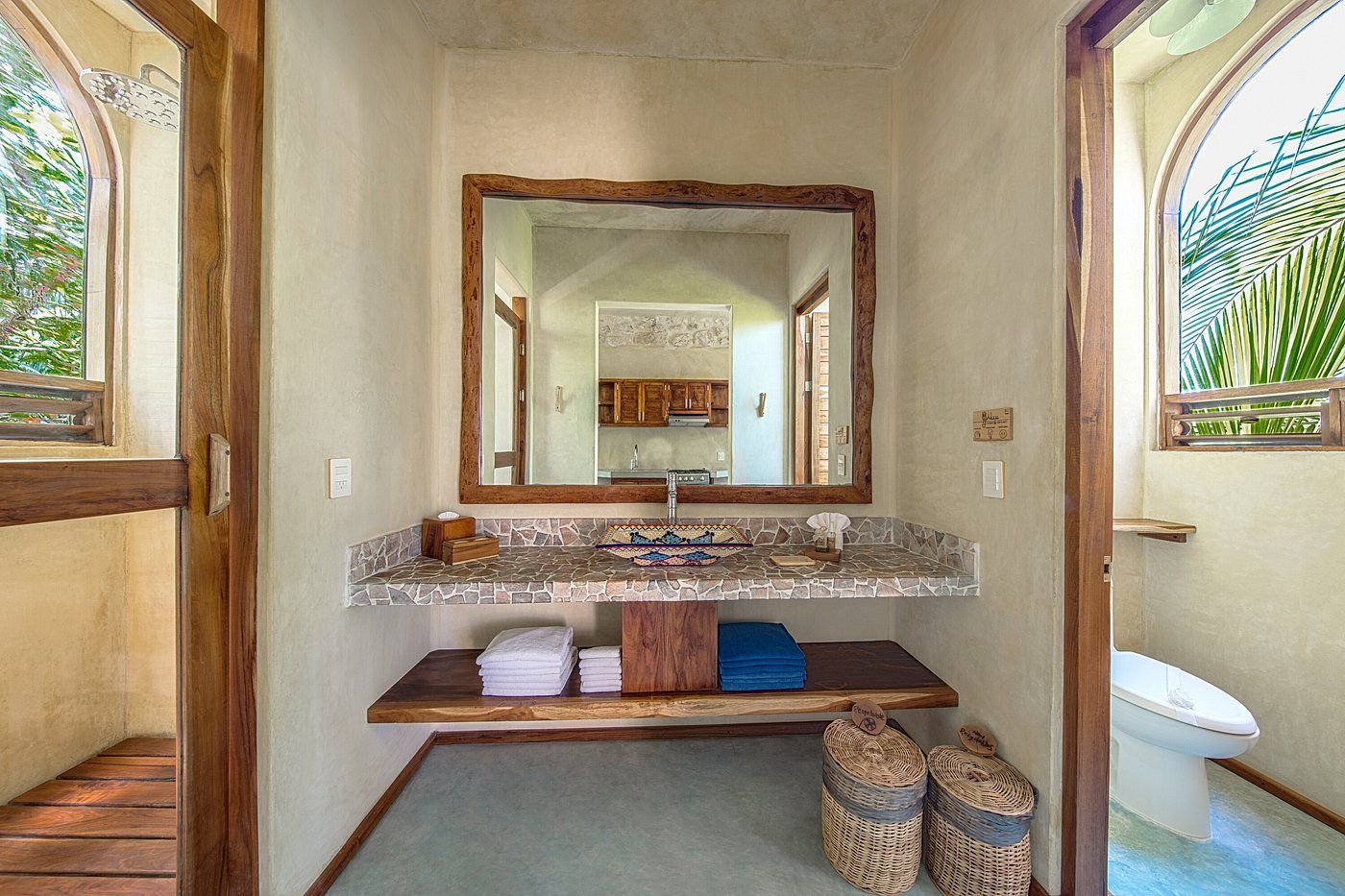 Bathroom with wood-framed mirror, granite countertop, wooden shelves, and arched windows.