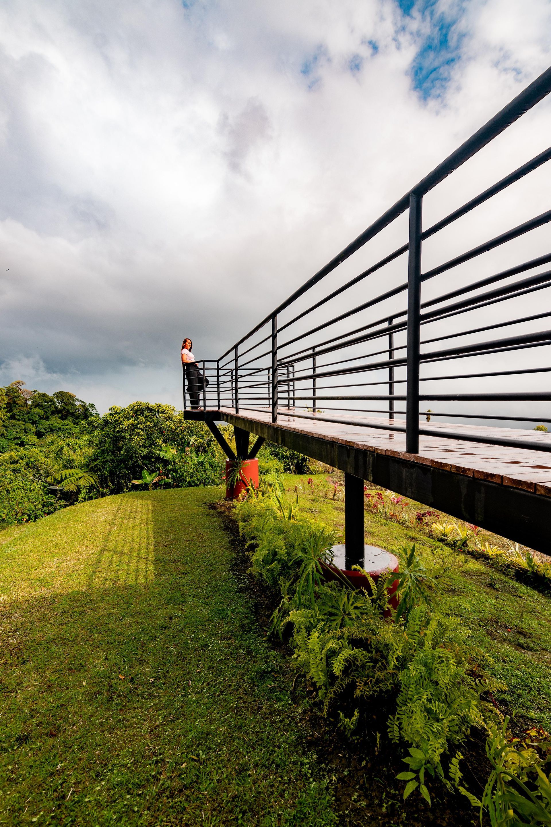 A person is standing on a bridge over a grassy field.