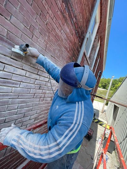 A man wearing a mask is painting a house siding.