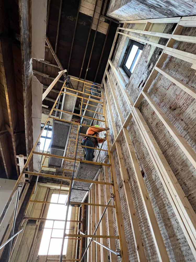 A man is standing on a ladder in a building under construction.