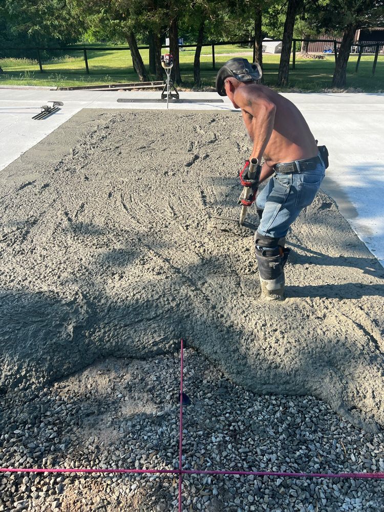 A shirtless man is working on a concrete driveway.